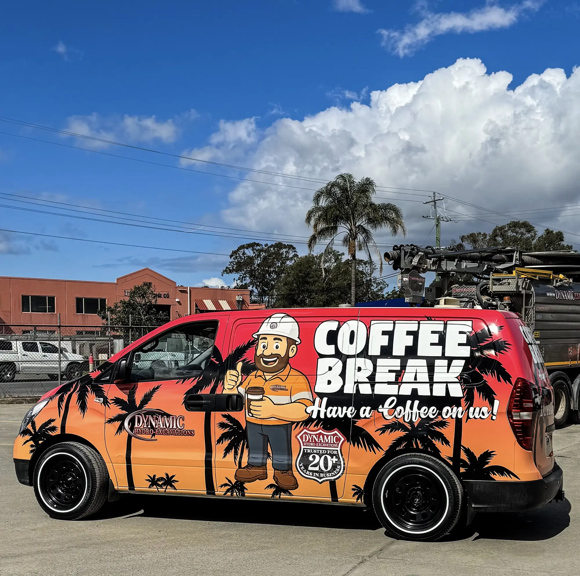 The Dynamic Coffee Break van, wrapped in orange and red palm tree livery reading "Coffee Break, have a coffee on us!", parked at a Dynamic yard