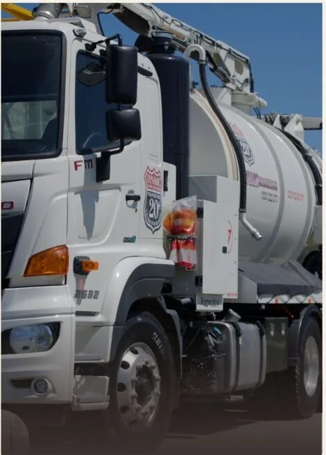 Front three-quarter view of a Dynamic Hydro Excavations vacuum excavation truck with its boom hose stowed above the tank