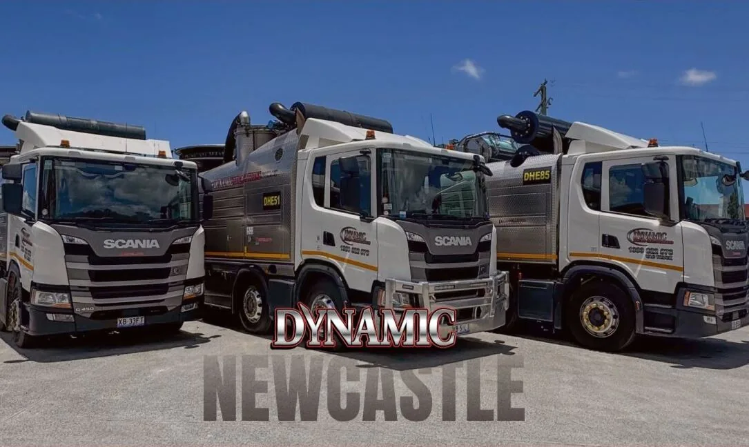 Three Dynamic Hydro Excavations Scania vacuum excavation trucks parked side by side in a depot yard under a clear sky