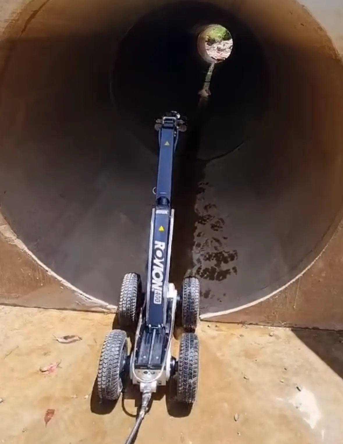 Wheeled CCTV inspection crawler driving into a large concrete stormwater pipe